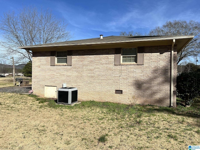 view of side of home with central AC and a lawn