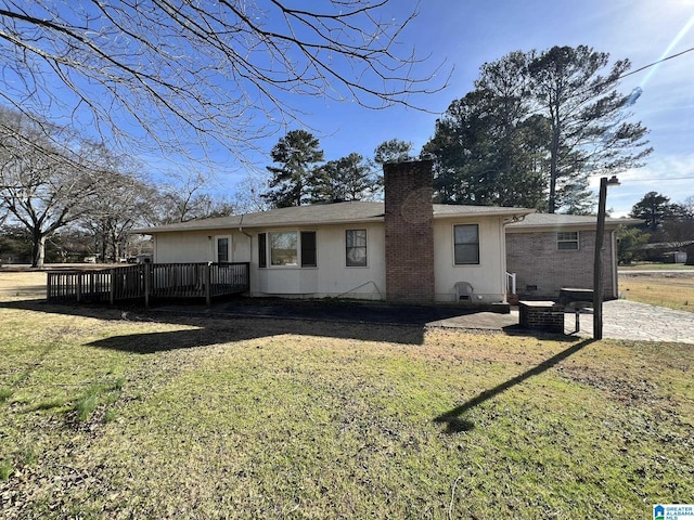 back of house featuring a wooden deck, a patio area, and a lawn