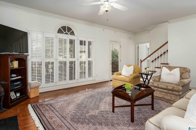 living area featuring visible vents, a ceiling fan, stairway, dark wood-style flooring, and crown molding