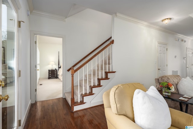 staircase with baseboards, wood finished floors, visible vents, and crown molding