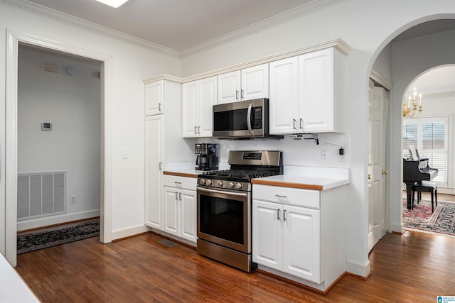 kitchen featuring stainless steel appliances, white cabinets, visible vents, and dark wood finished floors