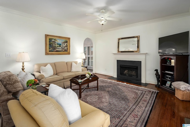 living room with dark wood-style floors, a fireplace with flush hearth, ornamental molding, and arched walkways