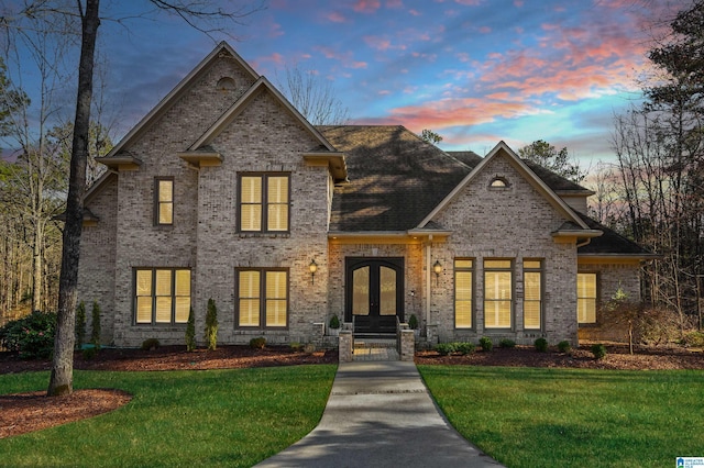 view of front of property with brick siding, a front yard, and french doors