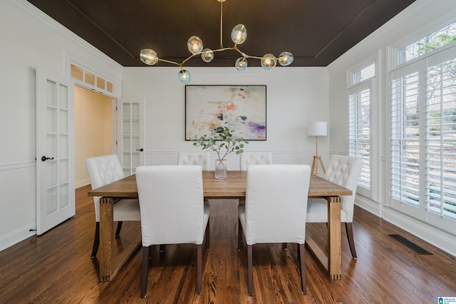 dining room featuring an inviting chandelier, dark wood finished floors, visible vents, and crown molding