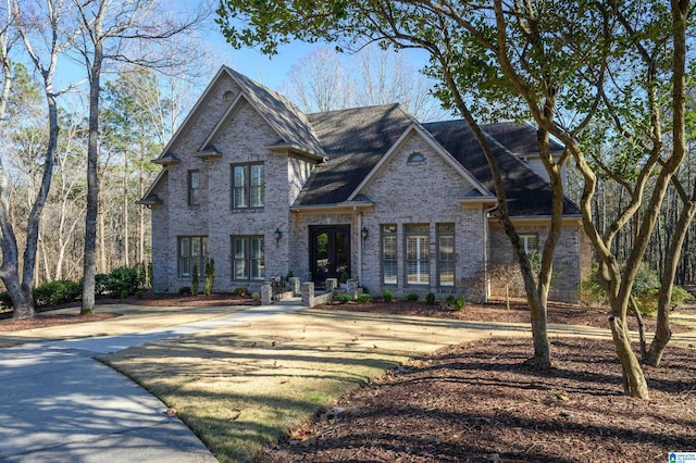 view of front of house with driveway, french doors, and brick siding