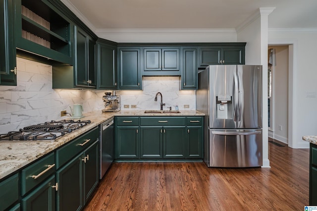 kitchen with light stone countertops, appliances with stainless steel finishes, green cabinetry, and a sink