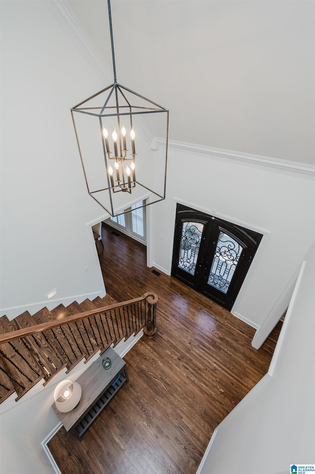 foyer entrance featuring stairway, dark wood-style flooring, an inviting chandelier, crown molding, and french doors