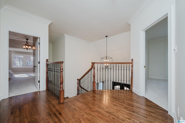 corridor featuring a chandelier, an upstairs landing, baseboards, dark wood finished floors, and crown molding