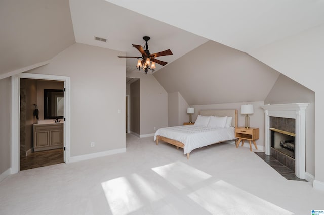 carpeted bedroom with a fireplace, visible vents, ensuite bathroom, vaulted ceiling, and baseboards