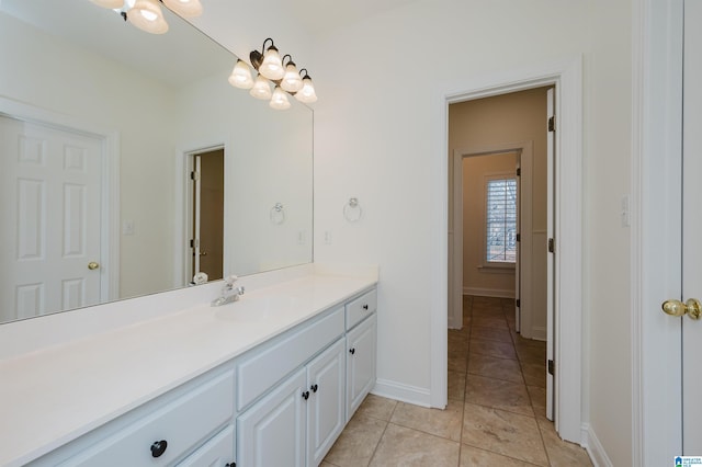 bathroom with tile patterned flooring, baseboards, a chandelier, and vanity