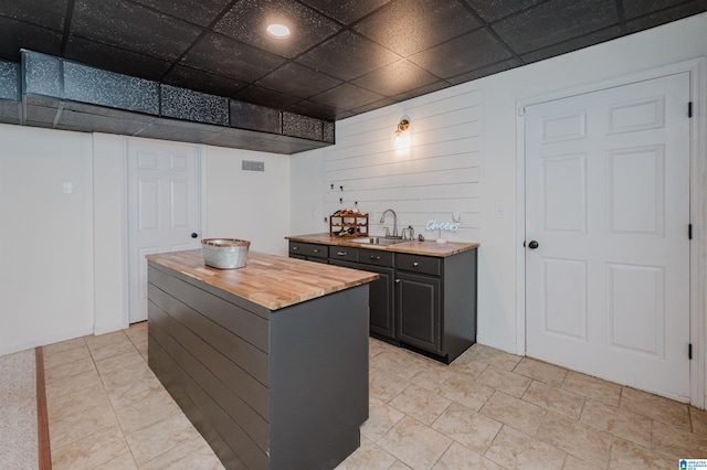 bar featuring a paneled ceiling, visible vents, and a sink