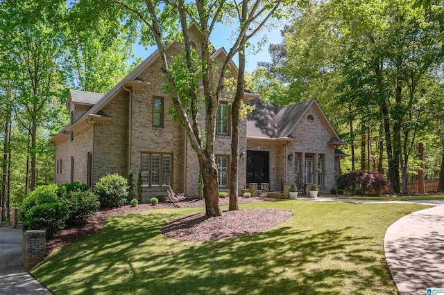 tudor-style house featuring brick siding and a front lawn