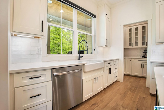 kitchen featuring light countertops, glass insert cabinets, white cabinetry, a sink, and dishwasher