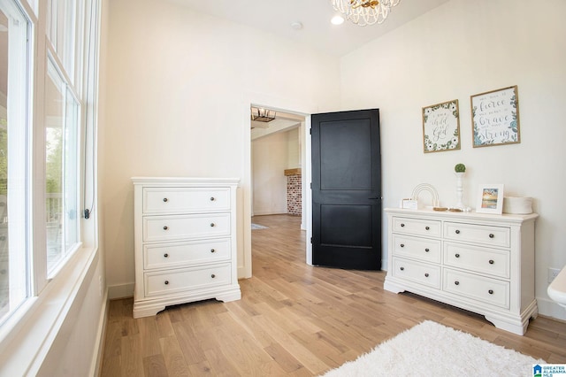 bedroom with light wood-type flooring, baseboards, and a chandelier