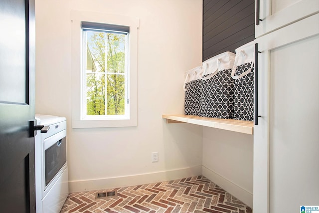 laundry room with brick floor, laundry area, visible vents, and baseboards