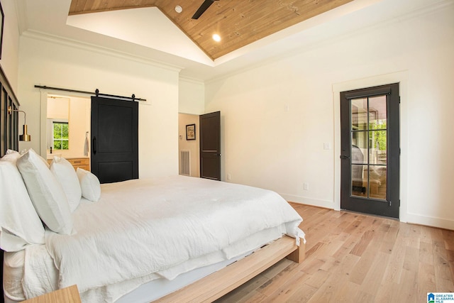 bedroom with a barn door, visible vents, baseboards, light wood-style flooring, and high vaulted ceiling