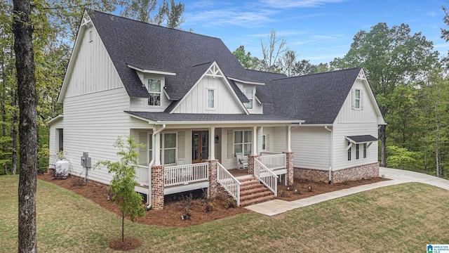 view of front of home featuring covered porch, a front lawn, and roof with shingles