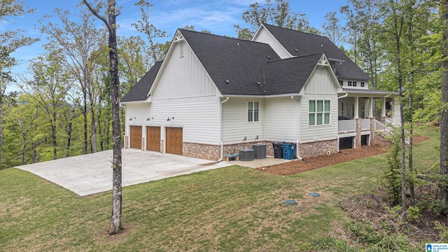 exterior space with covered porch, a garage, concrete driveway, roof with shingles, and a lawn