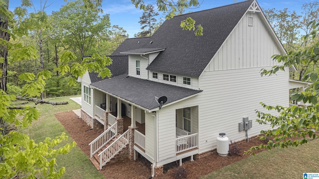 back of house with a porch, stairs, a yard, roof with shingles, and board and batten siding