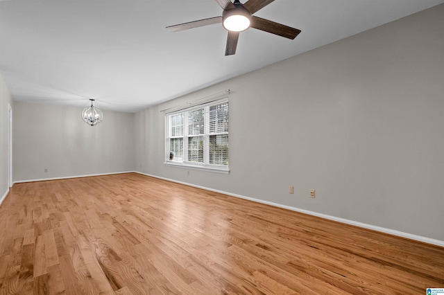 unfurnished room with ceiling fan with notable chandelier and light wood-type flooring