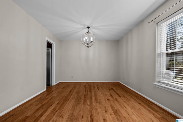 empty room with light wood-type flooring and a chandelier