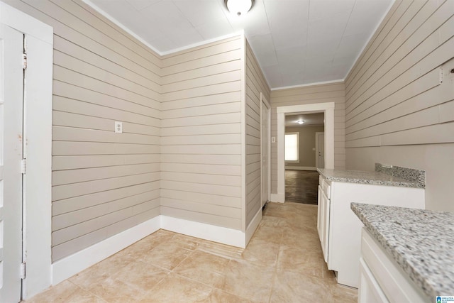 corridor with ornamental molding, light tile patterned flooring, and wood walls