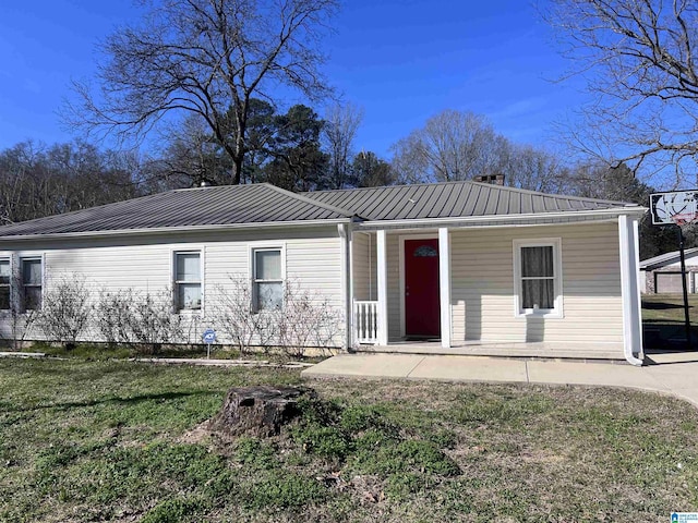 back of house featuring covered porch, metal roof, and a lawn