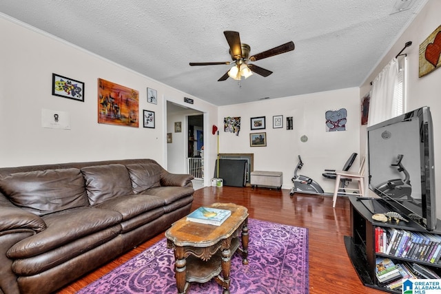living room with dark wood-style flooring, visible vents, ceiling fan, and a textured ceiling