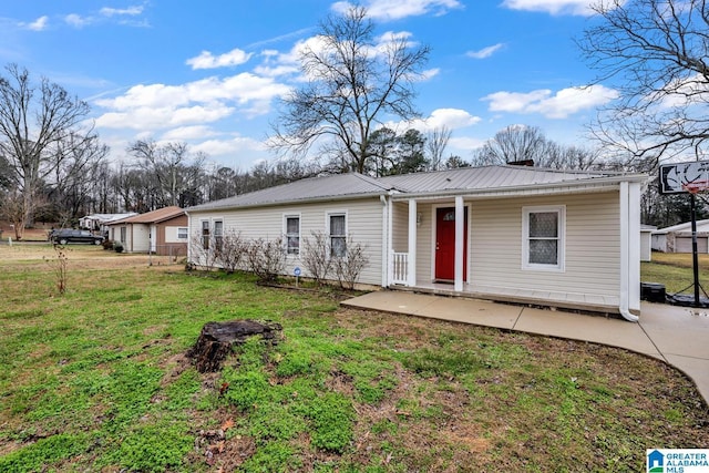 back of property featuring metal roof, a lawn, and a patio