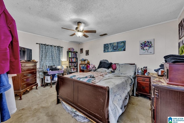 bedroom with visible vents, light colored carpet, ceiling fan, a textured ceiling, and crown molding