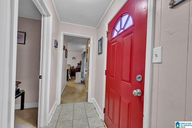 foyer entrance with a textured ceiling, light tile patterned flooring, light colored carpet, and baseboards