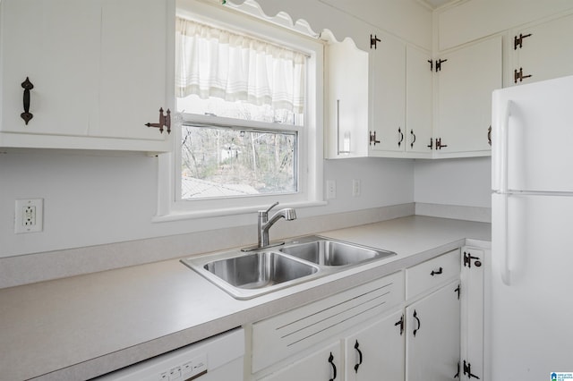 kitchen with white appliances, light countertops, a sink, and white cabinetry