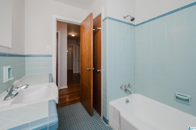 full bathroom featuring a sink, tile patterned flooring, washtub / shower combination, and tile walls