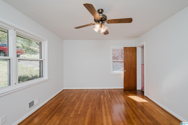 spare room featuring visible vents, ceiling fan, baseboards, and wood finished floors