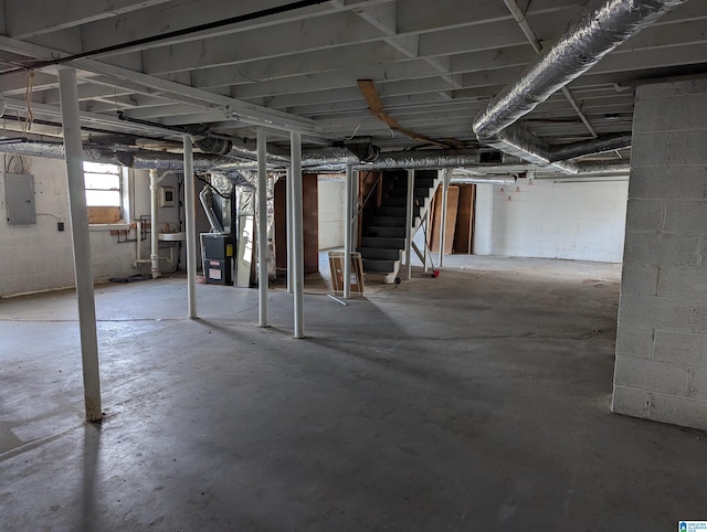 basement featuring electric panel, heating unit, and stairs