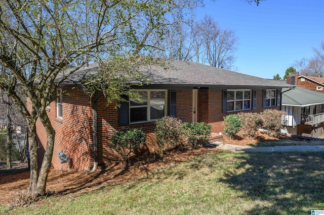 single story home featuring roof with shingles, a front lawn, and brick siding