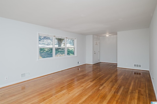 spare room featuring baseboards, visible vents, and wood finished floors