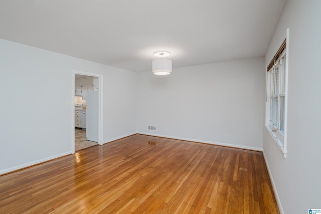 empty room featuring visible vents, baseboards, and wood finished floors