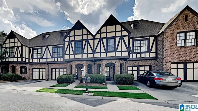 view of front of house featuring brick siding, stucco siding, a shingled roof, a garage, and driveway