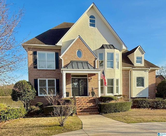 view of front of house featuring brick siding, a front lawn, and stucco siding