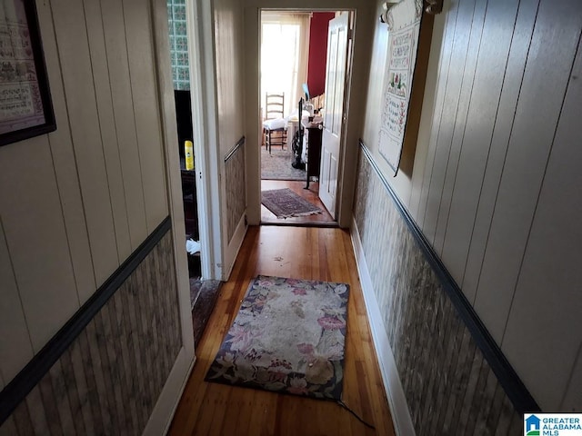 hall with wood walls and dark wood-style flooring
