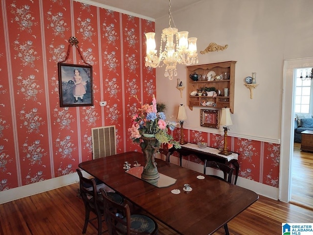 dining space with baseboards, wood finished floors, visible vents, and wallpapered walls