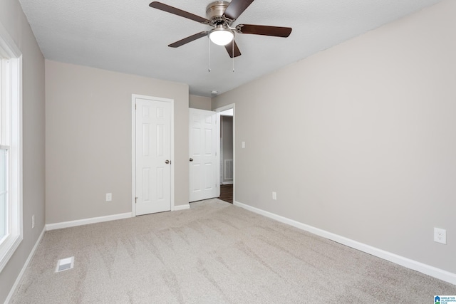 unfurnished bedroom featuring ceiling fan, a textured ceiling, and light colored carpet