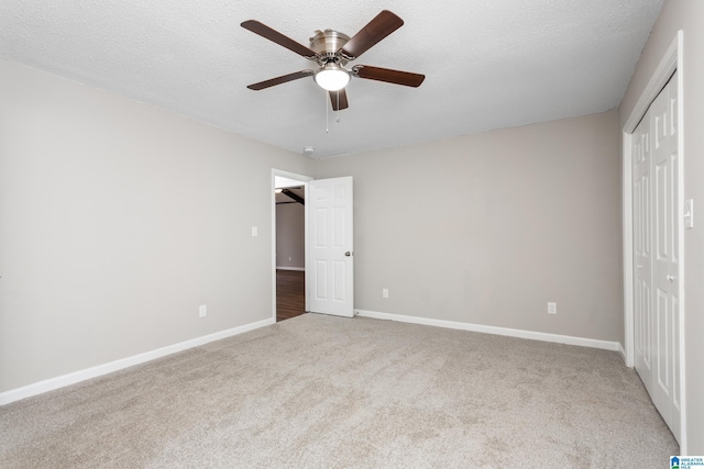 unfurnished bedroom featuring carpet, a closet, ceiling fan, and a textured ceiling