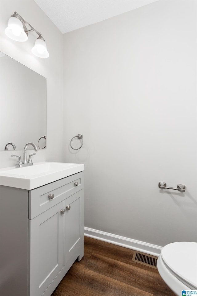 bathroom with toilet, vanity, and hardwood / wood-style floors