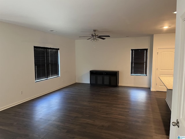 spare room with ceiling fan, visible vents, baseboards, and dark wood finished floors