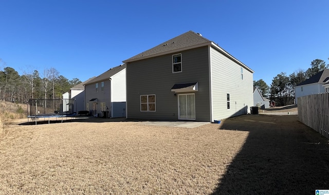 rear view of house with a trampoline, cooling unit, a patio area, and fence