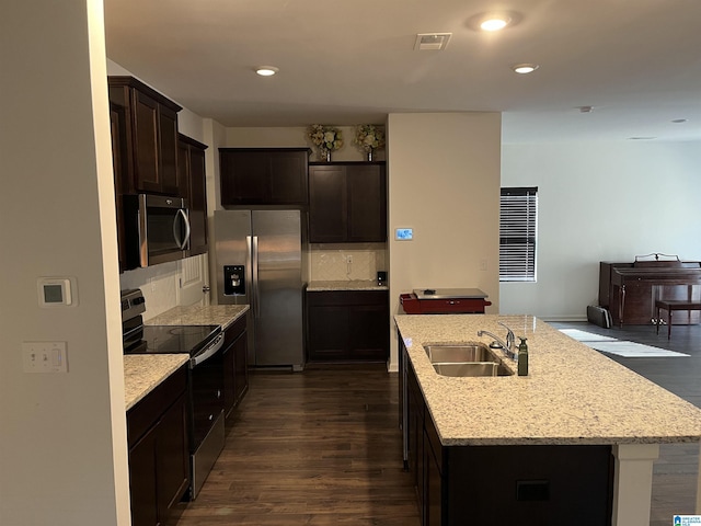 kitchen featuring stainless steel appliances, an island with sink, a sink, and dark wood finished floors