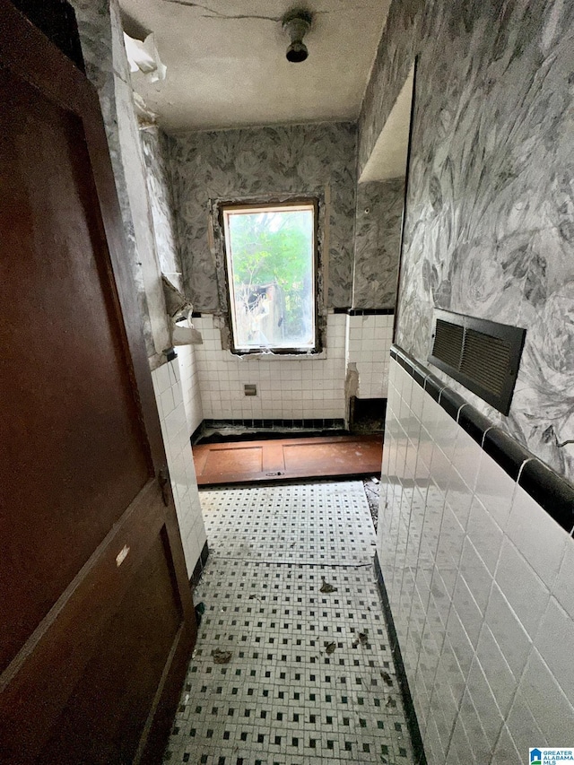 bathroom featuring a textured ceiling and tile walls