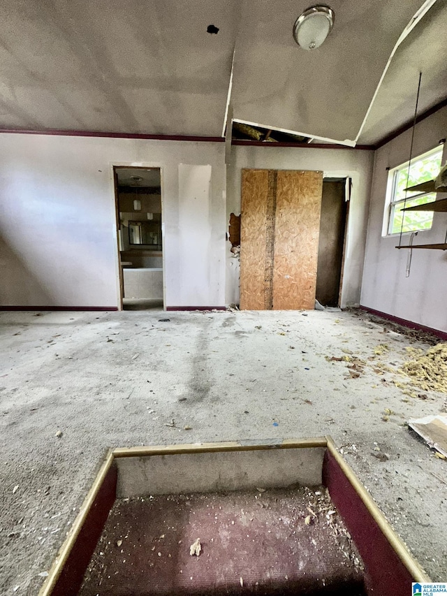 spare room featuring ornamental molding and vaulted ceiling